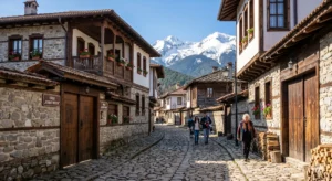 Traditional Bulgarian Renaissance architecture and cobblestone pavement on Neofit Rilski Street in Bansko with a view of the Pirin Mountains