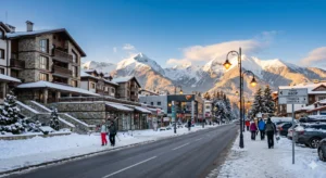 Modern Yavor Street in Bansko with a view of the snow-capped Pirin Mountains, luxury hotels and retail outlets in winter.
