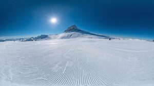 Panoramic view of the sunny slopes of the Bansko Plateau and Vihren Peak in the background.