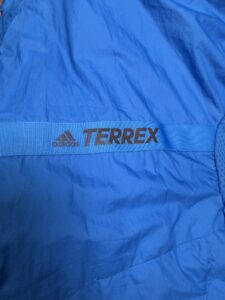 Синьо яке с лента и лого Adidas Terrex върху материята.