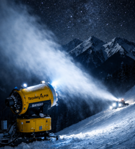 Жълт снегогенератор TechnoAlpin работи през нощта на писта в Банско на фона на Пирин.