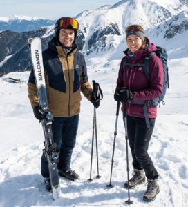 Мъж със ски екипировка Salomon и жена с екипировка за зимен туризъм позират на заснежен връх в Пирин над ски курорт Банско.