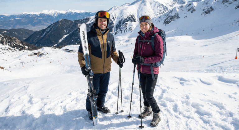 A man wearing Salomon ski gear and a woman wearing winter hiking gear pose on a snowy peak in Pirin above the Bansko ski resort.