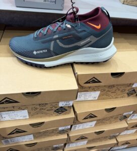 Маратонка Nike Trail с Gore‑Tex в тъмносиньо и бордо, изложена върху кашони с логото на Nike, с видима цена 109,99 евро.