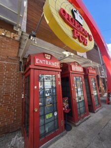 Страничен близък кадър на вратите на Queen's Pub в Банско, стилизирани като три червени лондонски телефонни кабини.