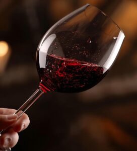 Чаша червено вино, разклащана за дегустация в уютна обстановка