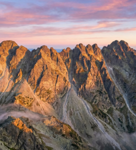 Алпинисти преминават по острия скален ръб на Траверсът на Стражите в Пирин планина.