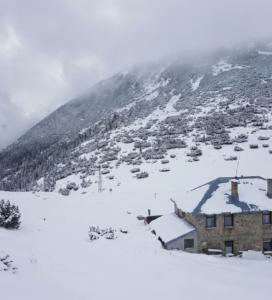 Каменната сграда на хижа Македония в Южна Рила, разположена на седловината Мечи проход под върховете.