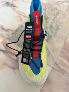 HOKA Mafate X Hike boot in blue and neon yellow with a red tongue and label indicating built-in RECCO rescue technology.