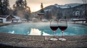 Glasses of red wine next to an outdoor mineral pool in Bansko with the snowy Pirin Mountains in the background.