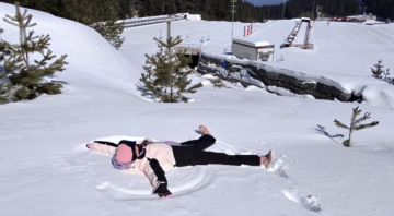 A man makes a snow angel in the snow in Bansko with a mountain in Pirin in the background