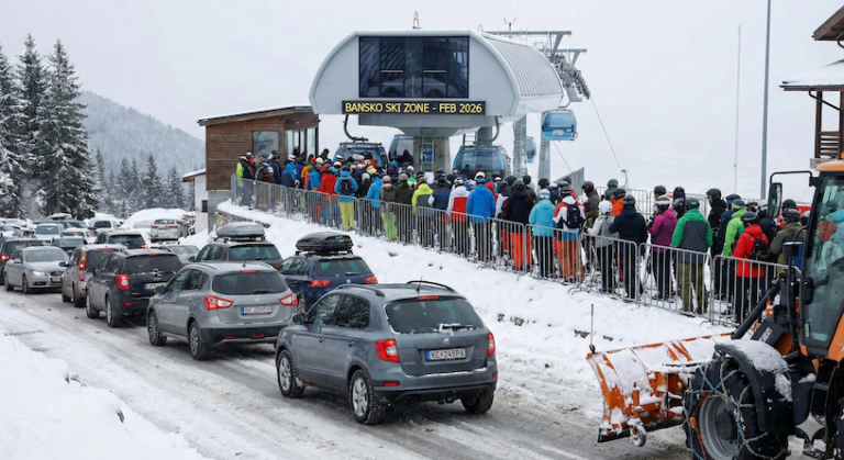 Snow-covered mountain road to the ski slopes in Bansko with a column of cars in winter.