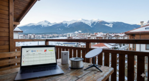 Comparison of internet providers in Bansko on a laptop with a view of Pirin, Starlink antenna, 5G router and fiber optic cable on a terrace