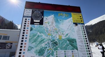 Information board with a map of the Bansko ski area against a background of a bright blue winter sky and sun.