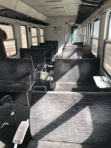 Интериор на почти празен влаков вагон с редици сиви седалки