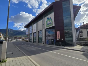 The building of the closed Mall Bansko against the backdrop of the snow-capped peaks of the Pirin Mountains